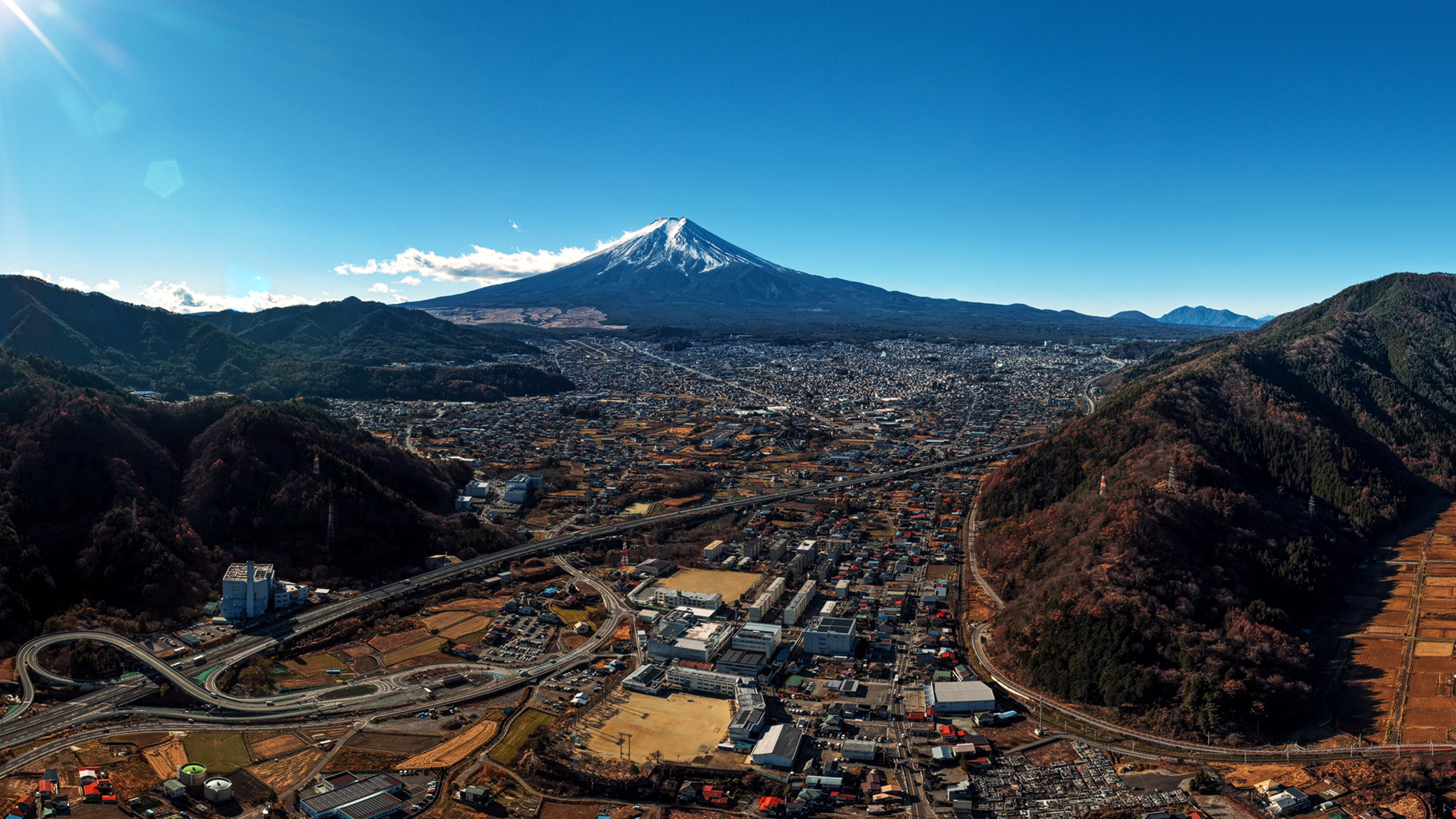 富士山と富士吉田市街地を高高度から俯瞰したパノラマ空撮写真