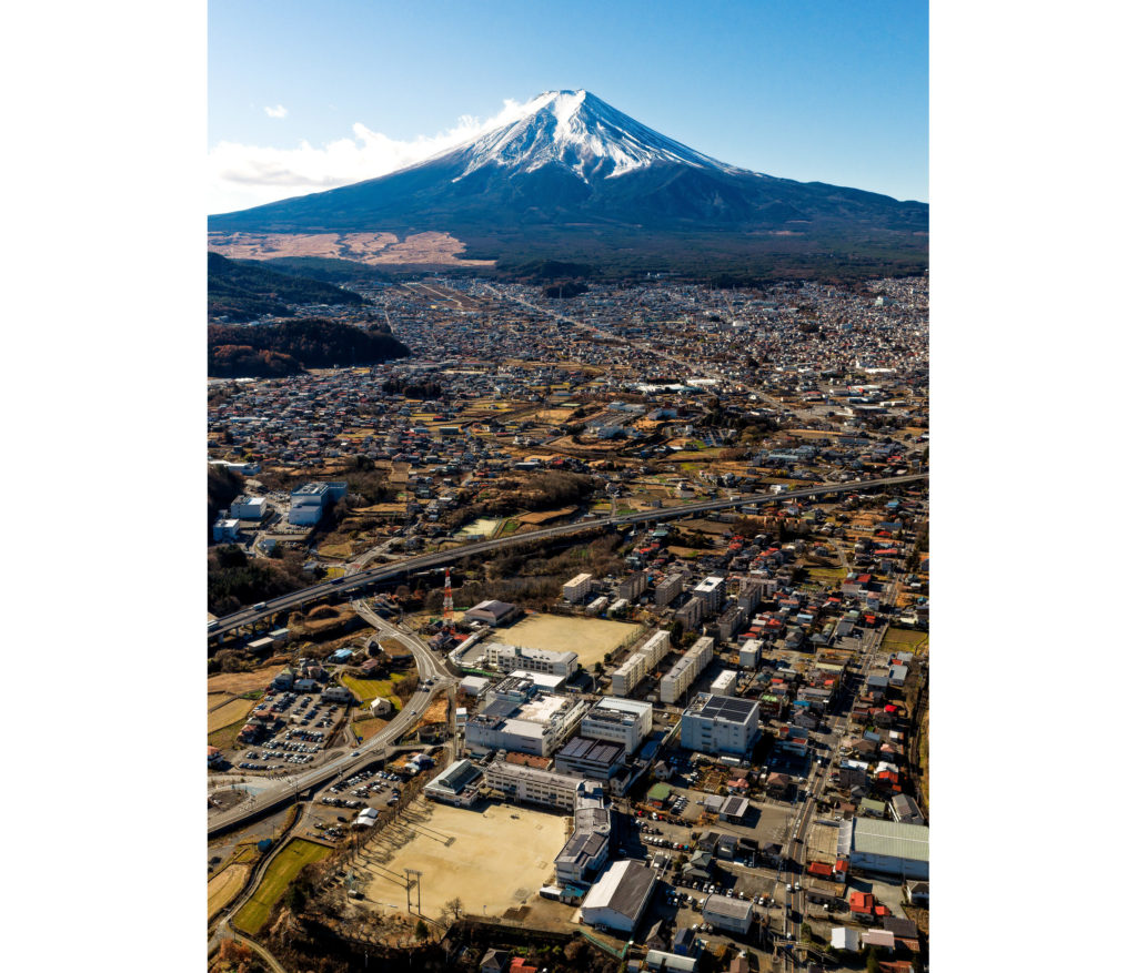 富士山を背景に、シチズン電子株式会社の社屋を300m上空から撮影した縦構図の空撮写真